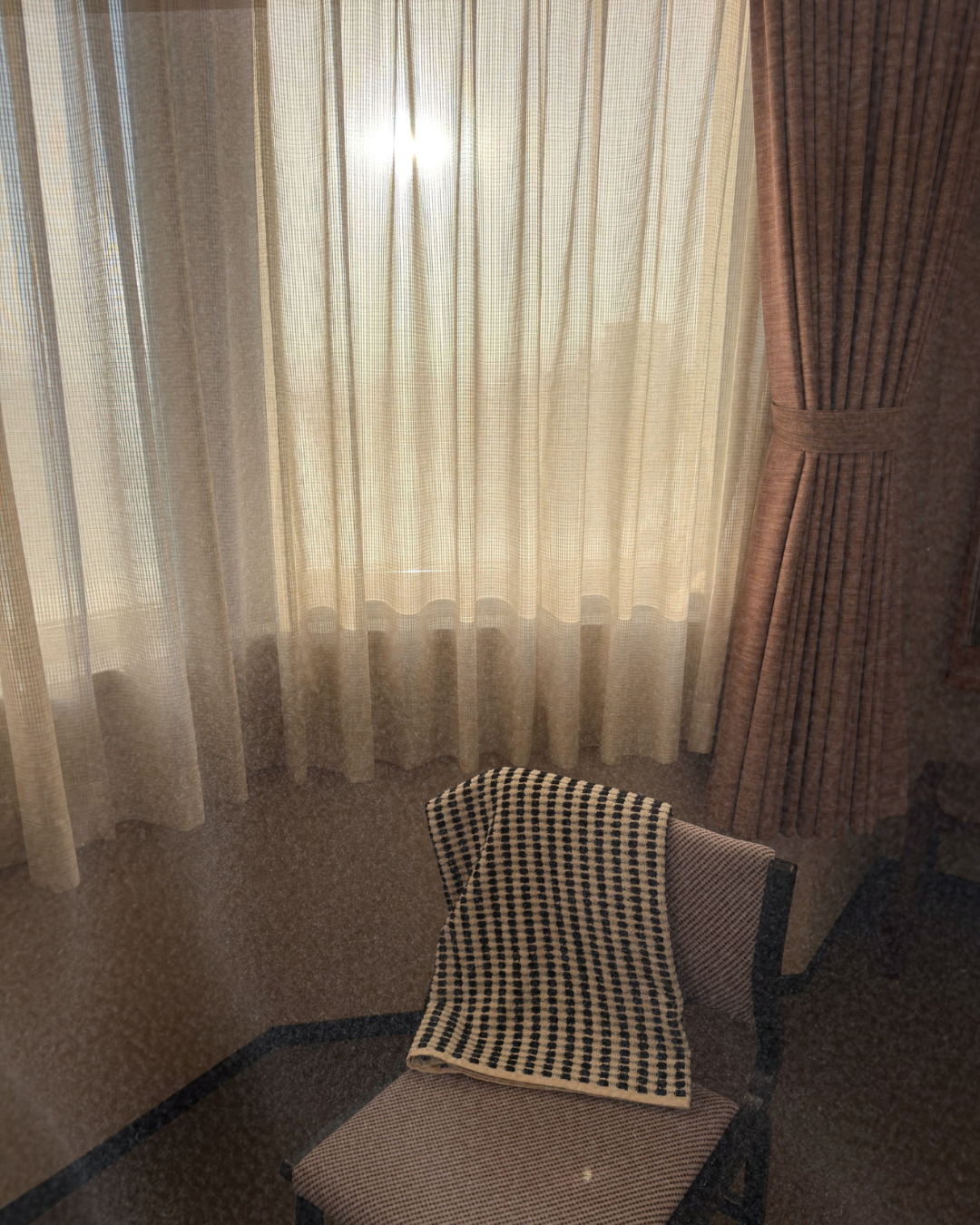Chair with a checkered bath towel by mandisgn in front of sheer curtains