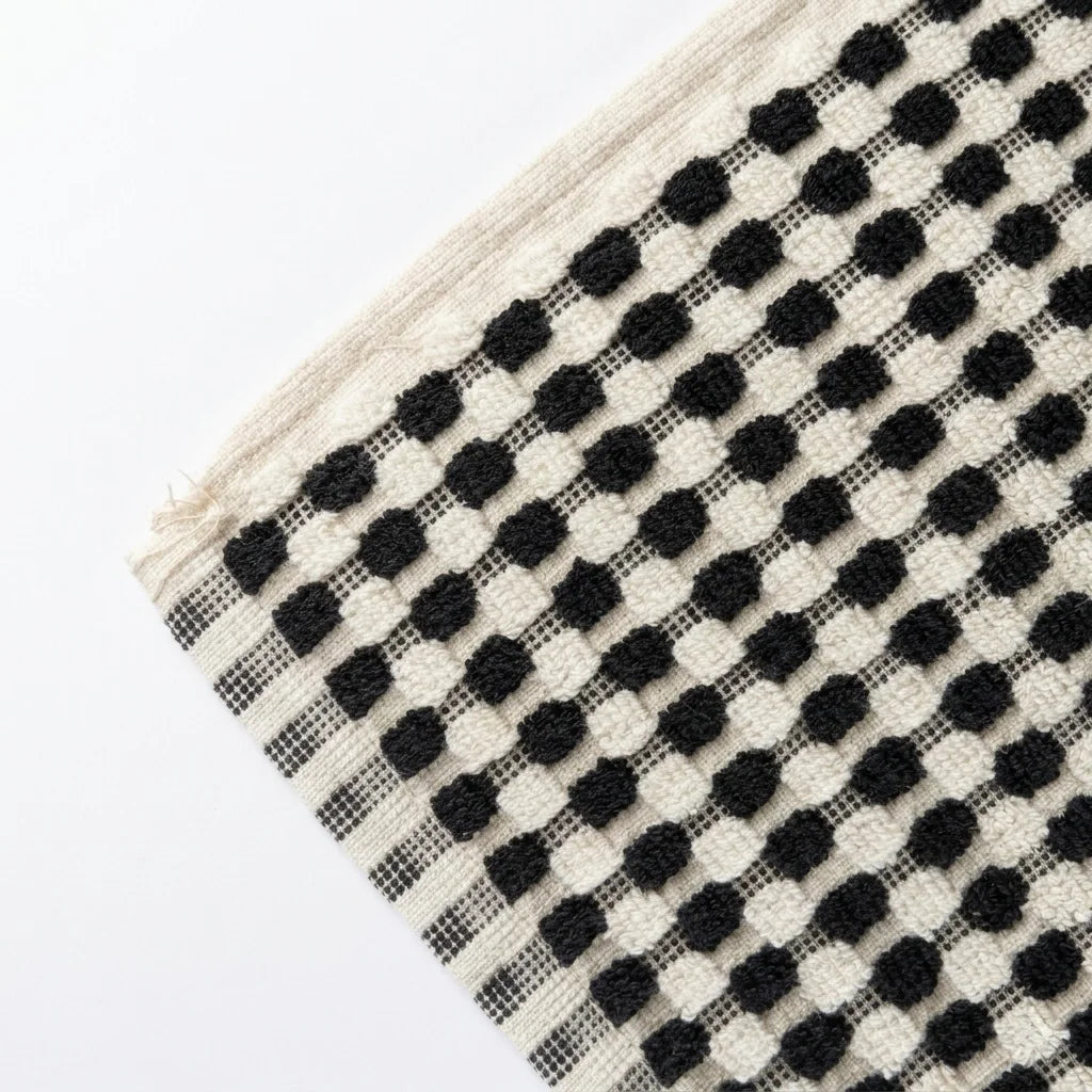 Black and white checkered bath towel with a textured pattern on a white background