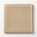 Beige waffle grid bath towel on a white background