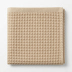Beige waffle grid bath towel on a white background