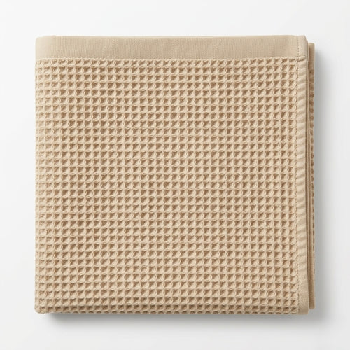Beige waffle grid bath towel on a white background