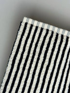 Close-up of a black and white striped bath towel on a light gray background