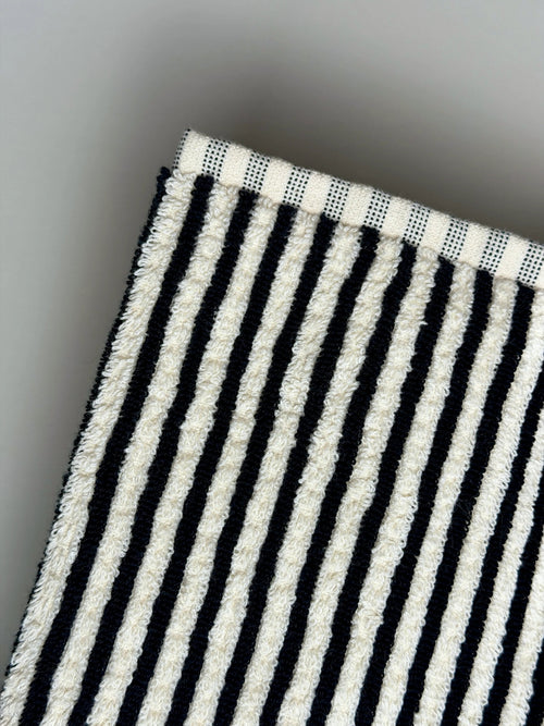 Close-up of a black and white striped bath towel on a light gray background