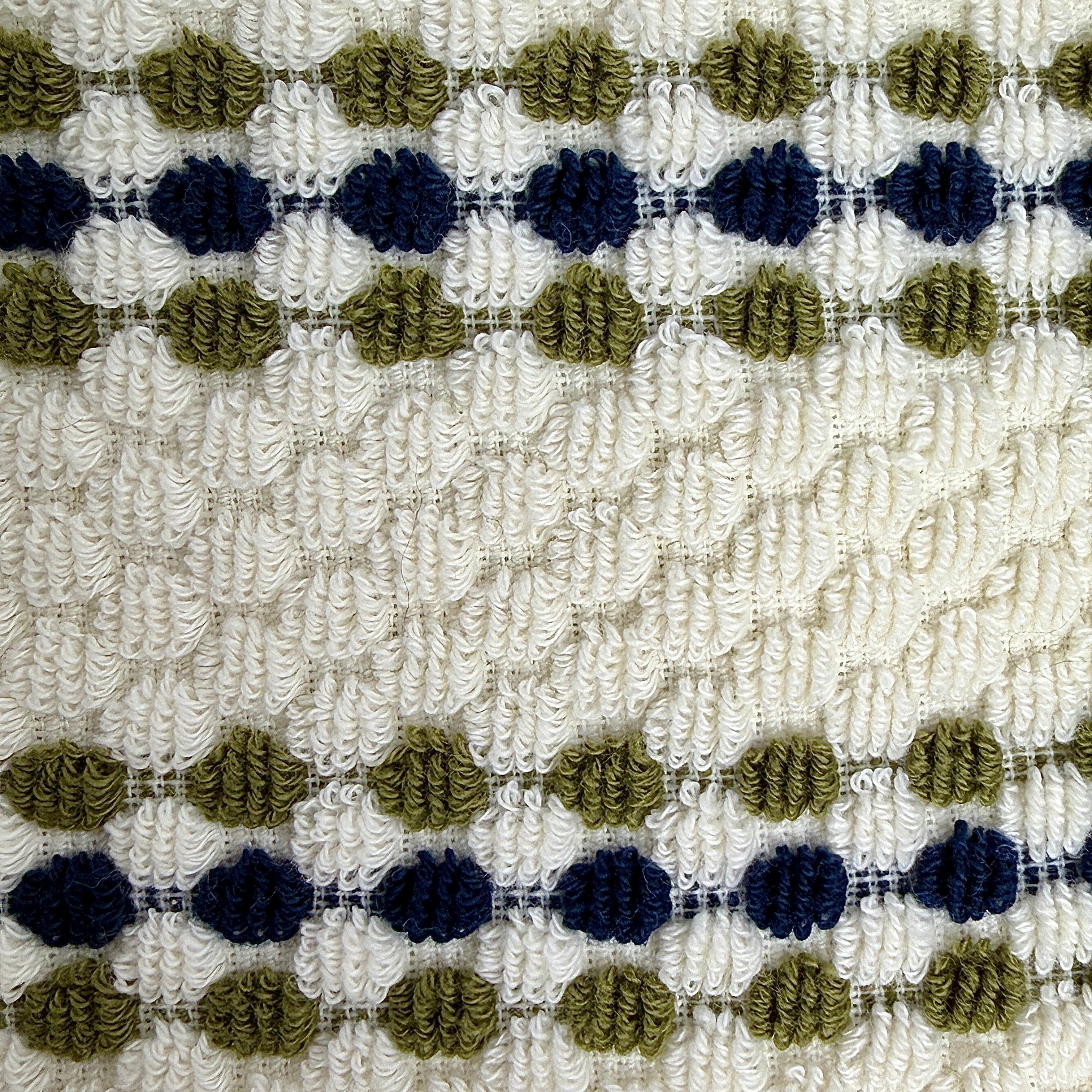 Close-up of a textured ath towel with a pattern of blue and green shapes on a beige background